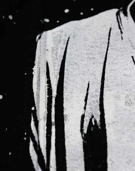 a white all over print on a black shirt showing imperfections in printing over the seams