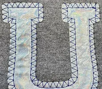 photo of a custom metallic fabric appliqued on a grey sweatshirt