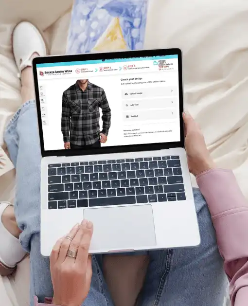 a photo of a person on a laptop designing a customized flannel in the BrokenArrowWear online design studio