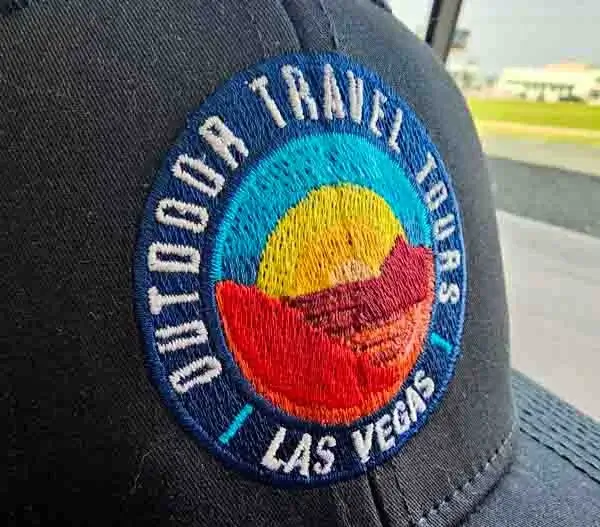 Embroidered outdoor travel tours patch on black custom trucker hat