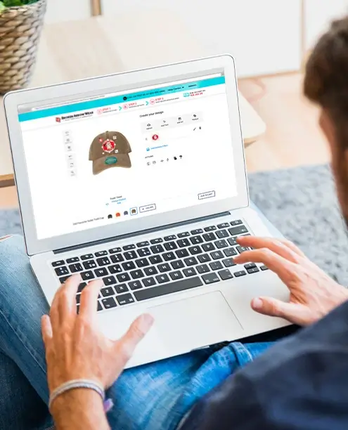 a photo of a person on a laptop designing a custom hat in the BrokenArrowWear online design studio