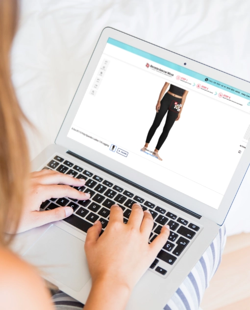 a photo of a person on a laptop designing custom women's leggings in the BrokenArrowWear online design studio