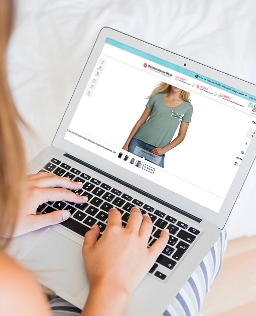 a photo of a person on a laptop designing a women's scoop neck t-shirt in the BrokenArrowWear online design studio