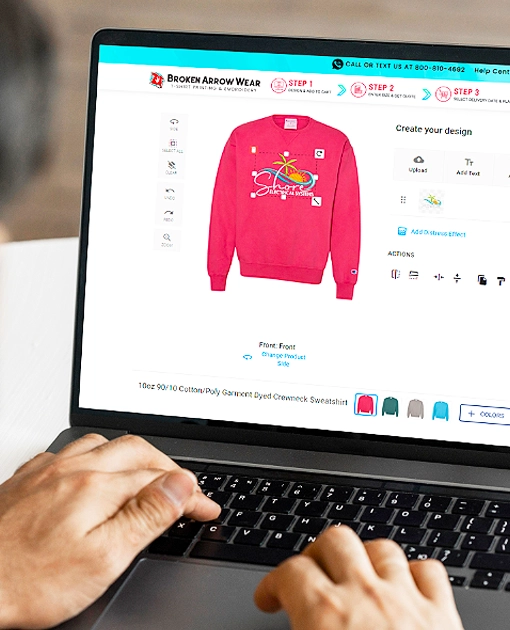 person on a laptop designing a pink crewneck sweatshirt in the broken arrow wear online design tool. 