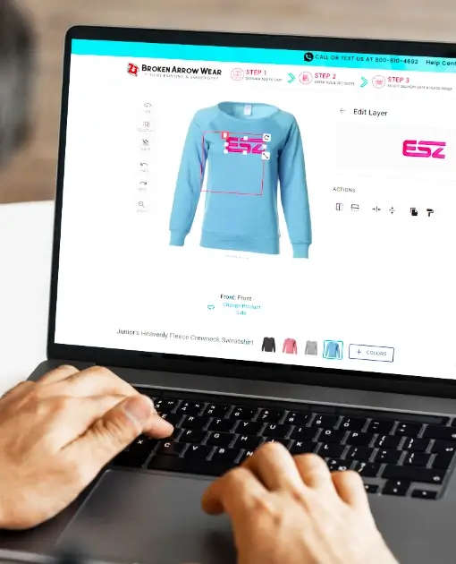 person on a laptop creating a custom women's crewneck sweatshirt in an online design tool