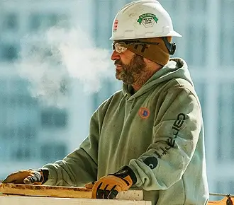 a man wearing a hard hat on a worksite wearing a customized heavyweight carhartt hoodie