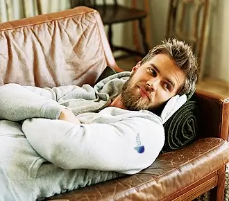 a man laying on a couch wearing a hoodie with a design on the sleeve