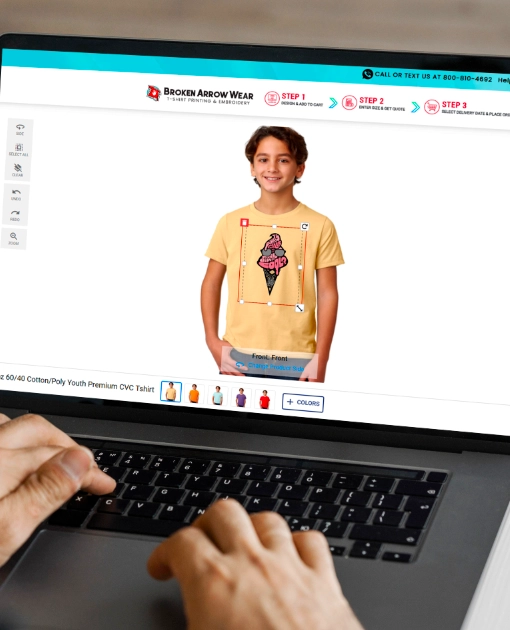 Hands on a laptop designing a youth tee in the Broken Arrow Wear online designer