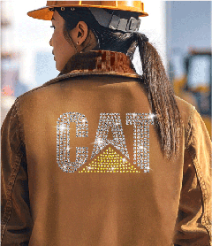 CAT construction logo in yellow and clear rhinestones on the back of a brown canvas work jacket.