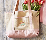 a cream boat tote bag with pink bottom and handles