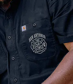 Black work shirt pocket with a reflective ink San Antonio Fire Department logo printed on it showing how reflective screen printing looks under light.